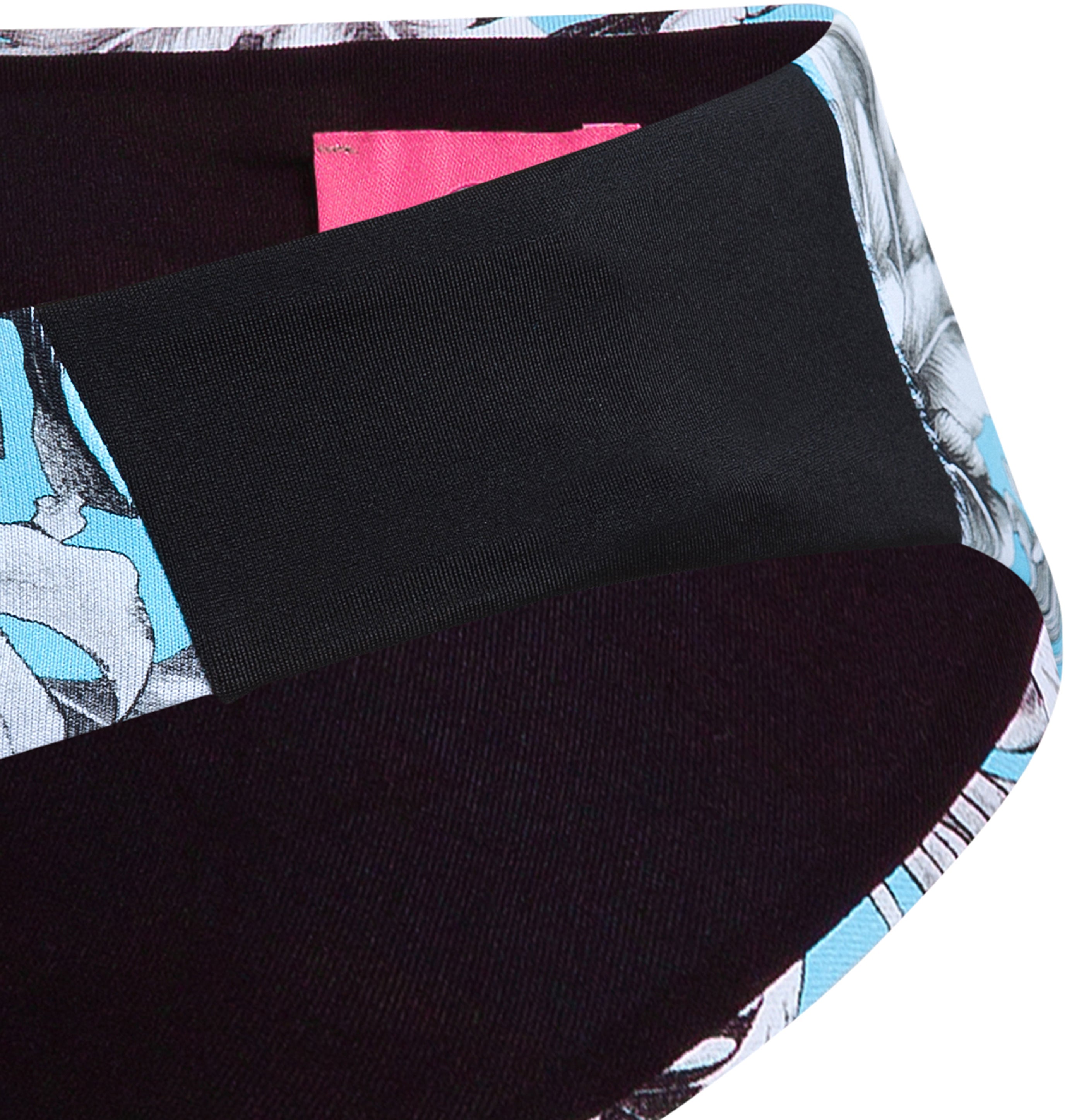 Close-up of the bottom of the Eniqua swimsuit with floral pattern, wide black waistband, subtle pink label on the inside and discreet bikini details with pencil drawing.