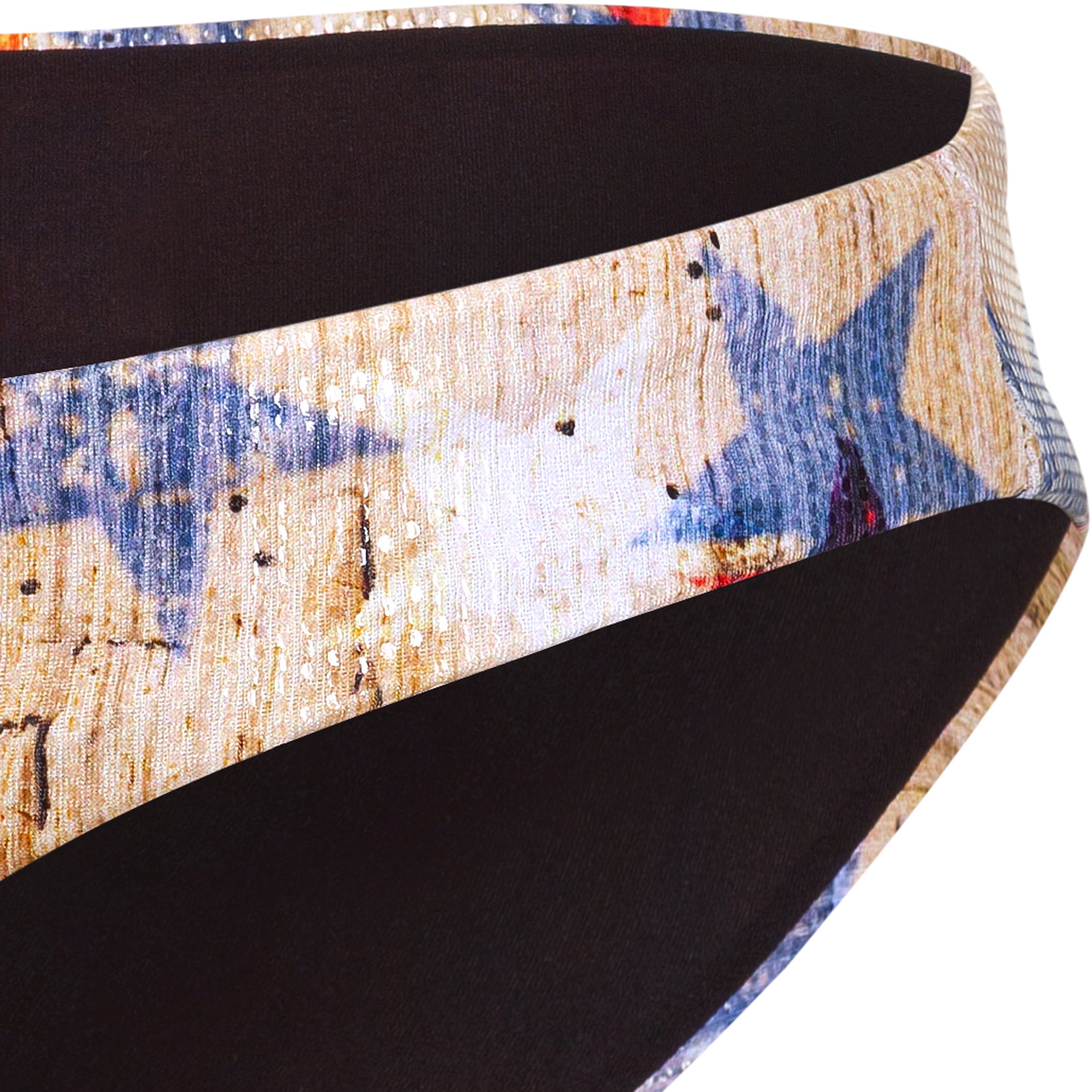 Close-up of a triangle bikini bottom by Eniqua, made in Italy, with a distorted star pattern in blue, beige and red.