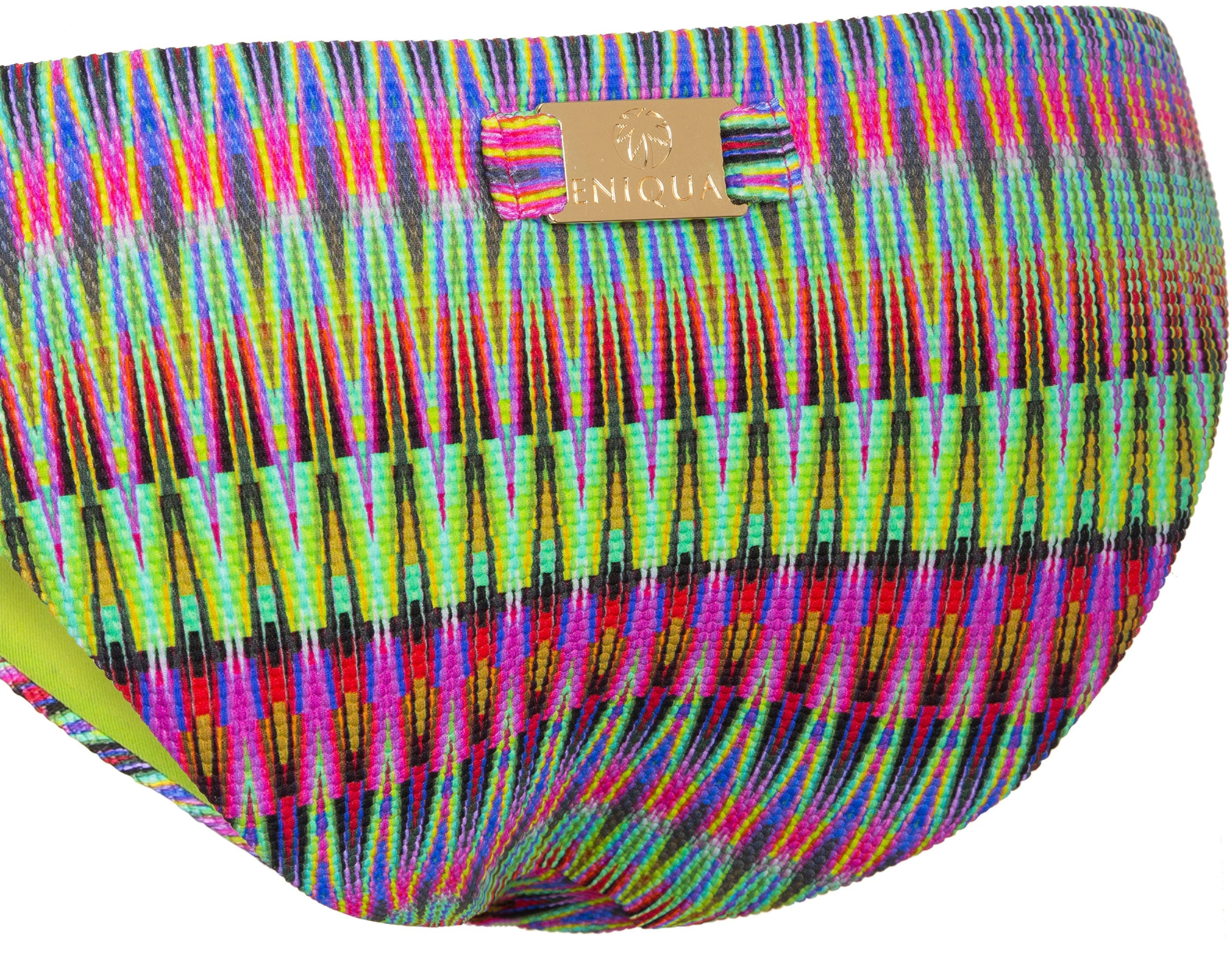 Close-up of colourful, patterned bikini bottoms with a gold Eniqua label on the waistband made from luxurious 3D fabric.