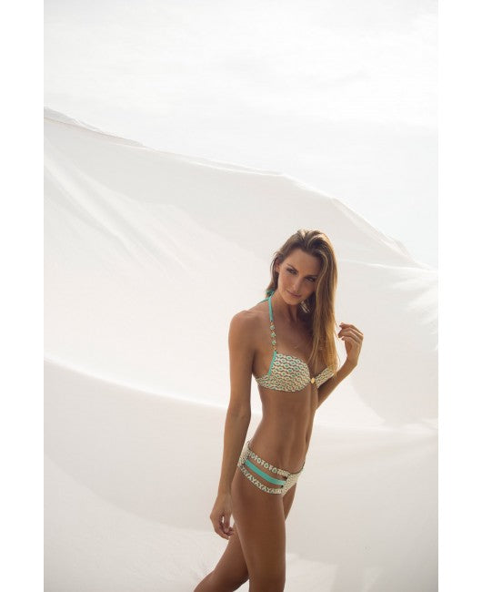A woman shows off an Italian push-up bikini by Eniqua outside in front of a white fabric backdrop, looking confidently into the camera.